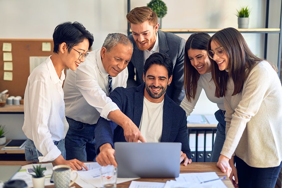 Employee Benefits - Group of Employees Helping Their Colleague on Laptop in the Office